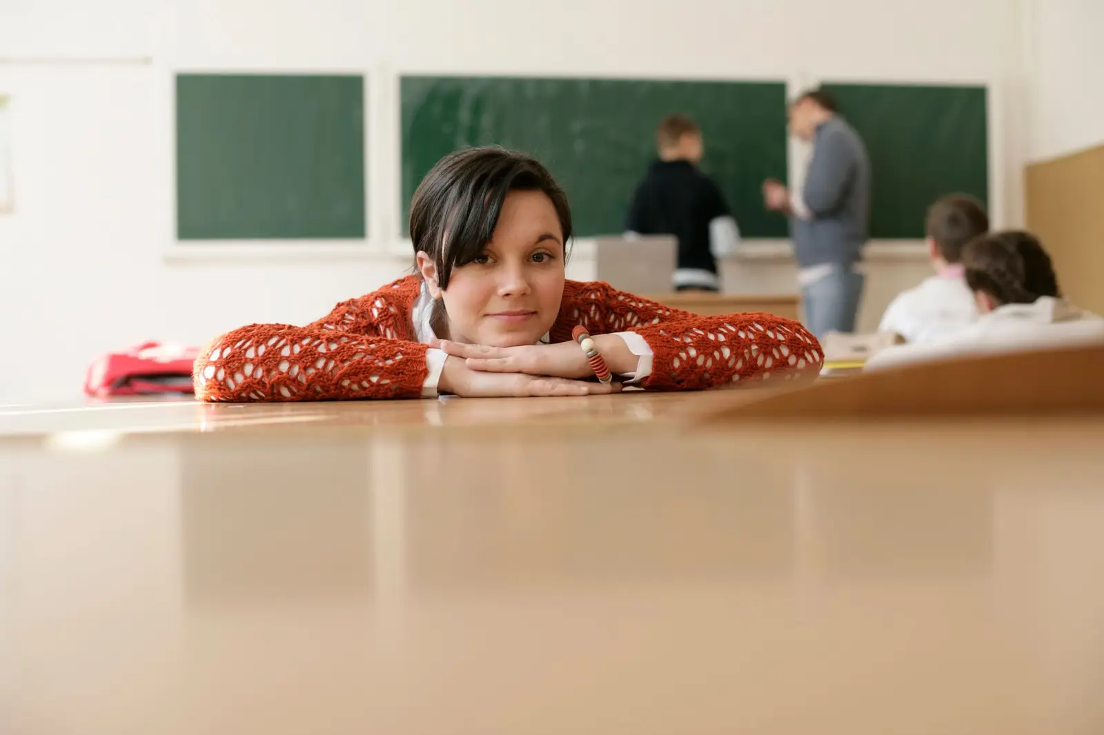 A student resting her head on her arms at a classroom desk