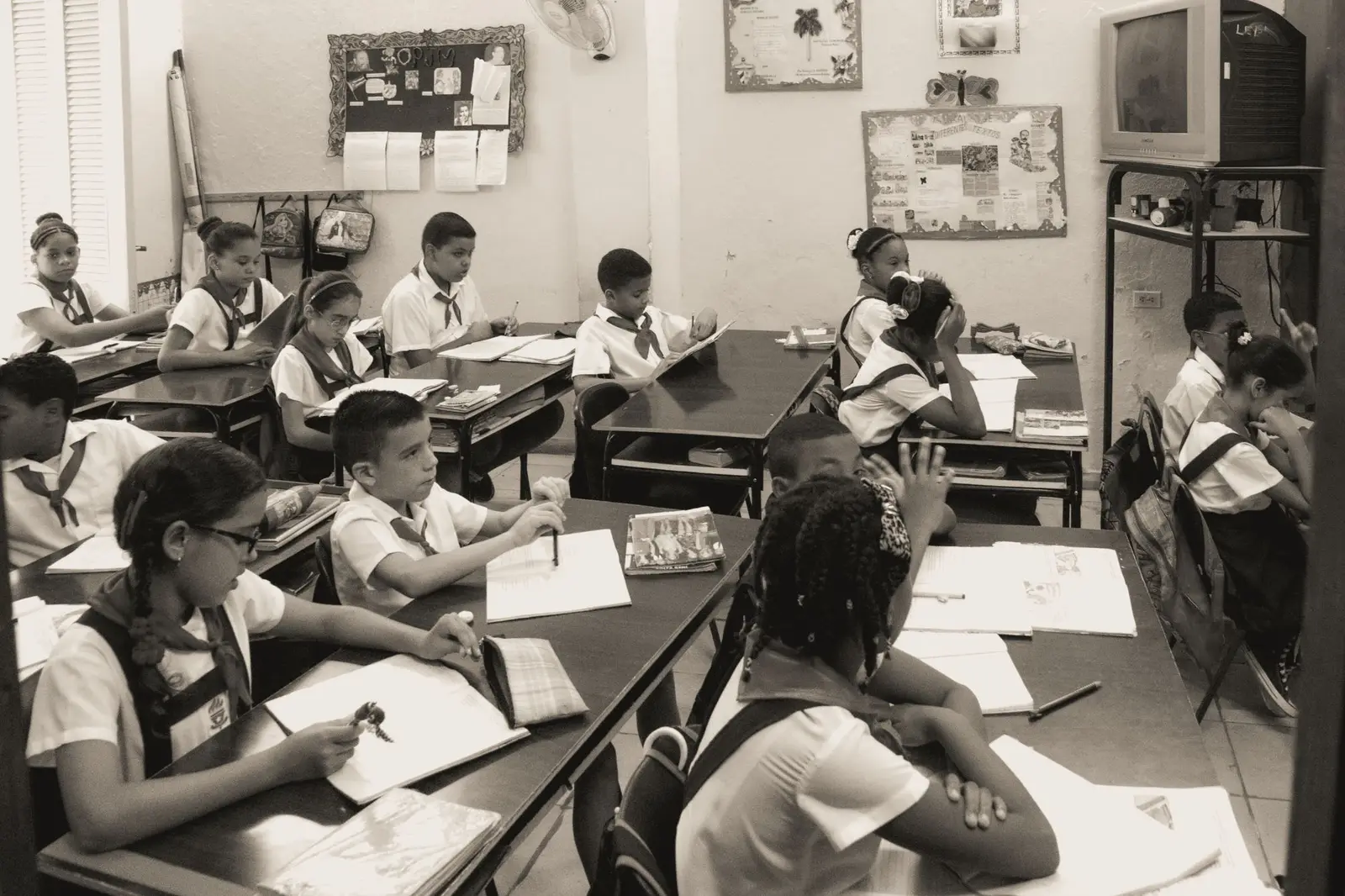 Children working at desks in a primary classroom, in black and white