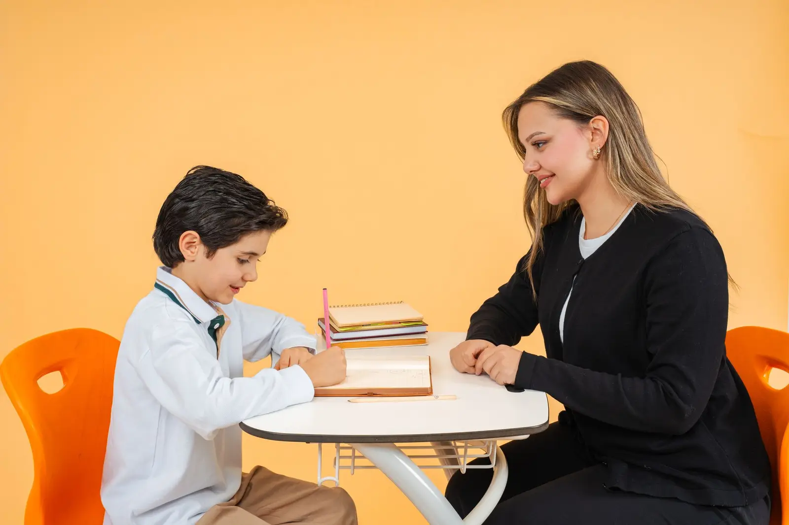A teacher and a boy working together at a table in a bright classroom