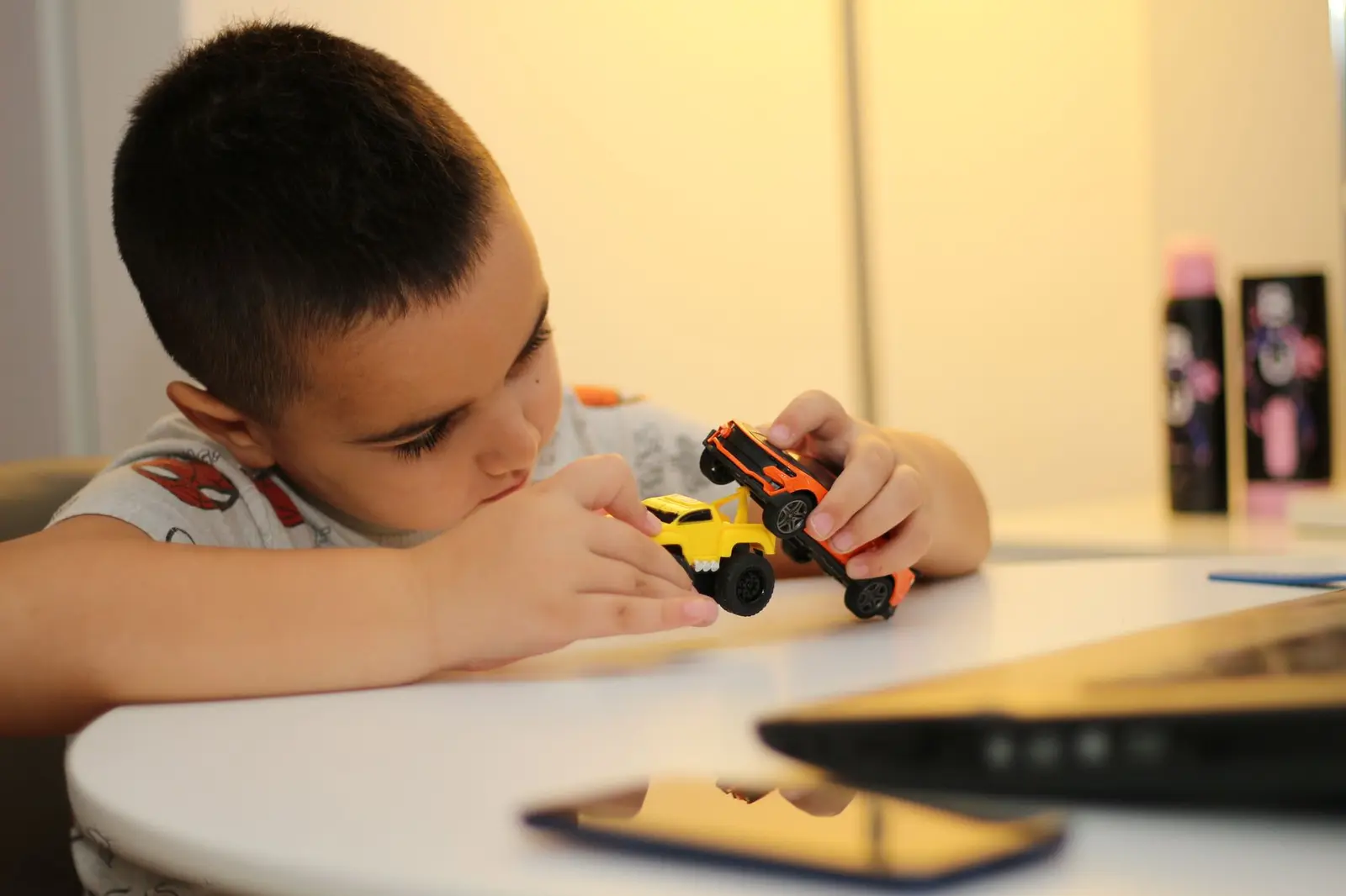 A boy focused on playing with a toy car at a table