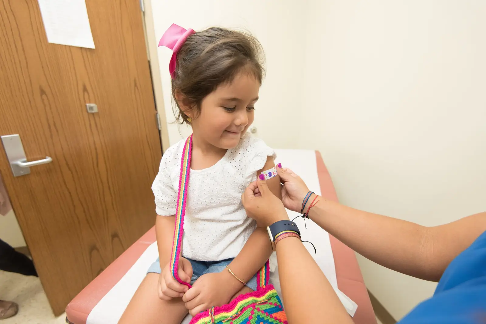 A nurse putting a bandage on a girl's arm after a vaccination