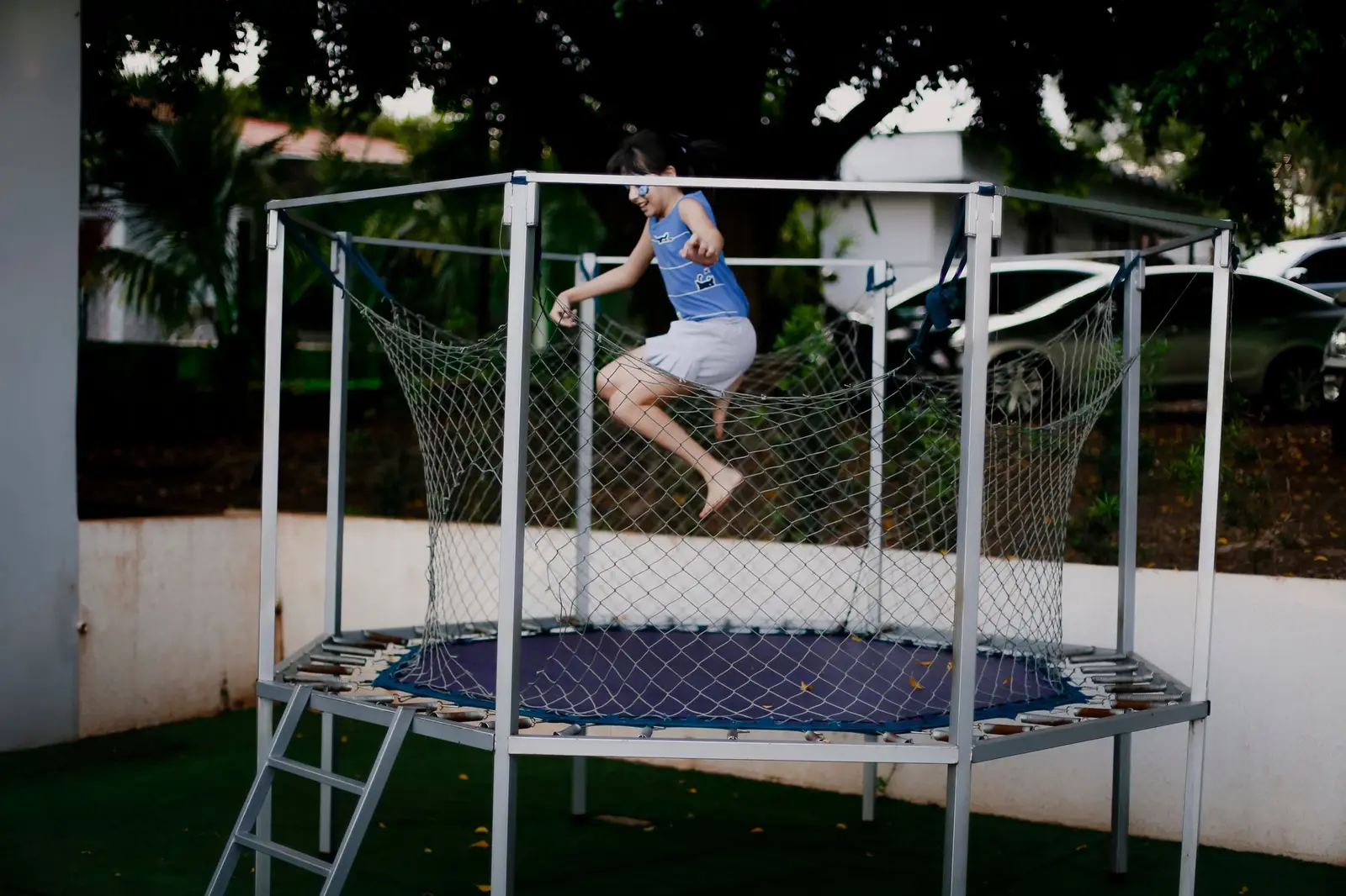A girl jumping on a backyard trampoline