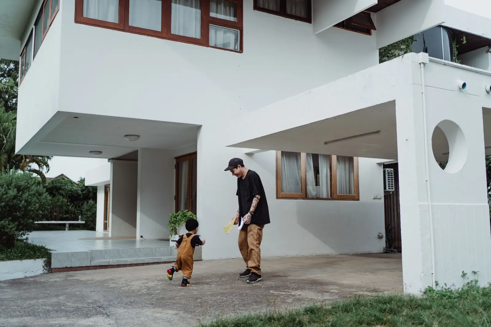 A father and young child playing outside a modern house