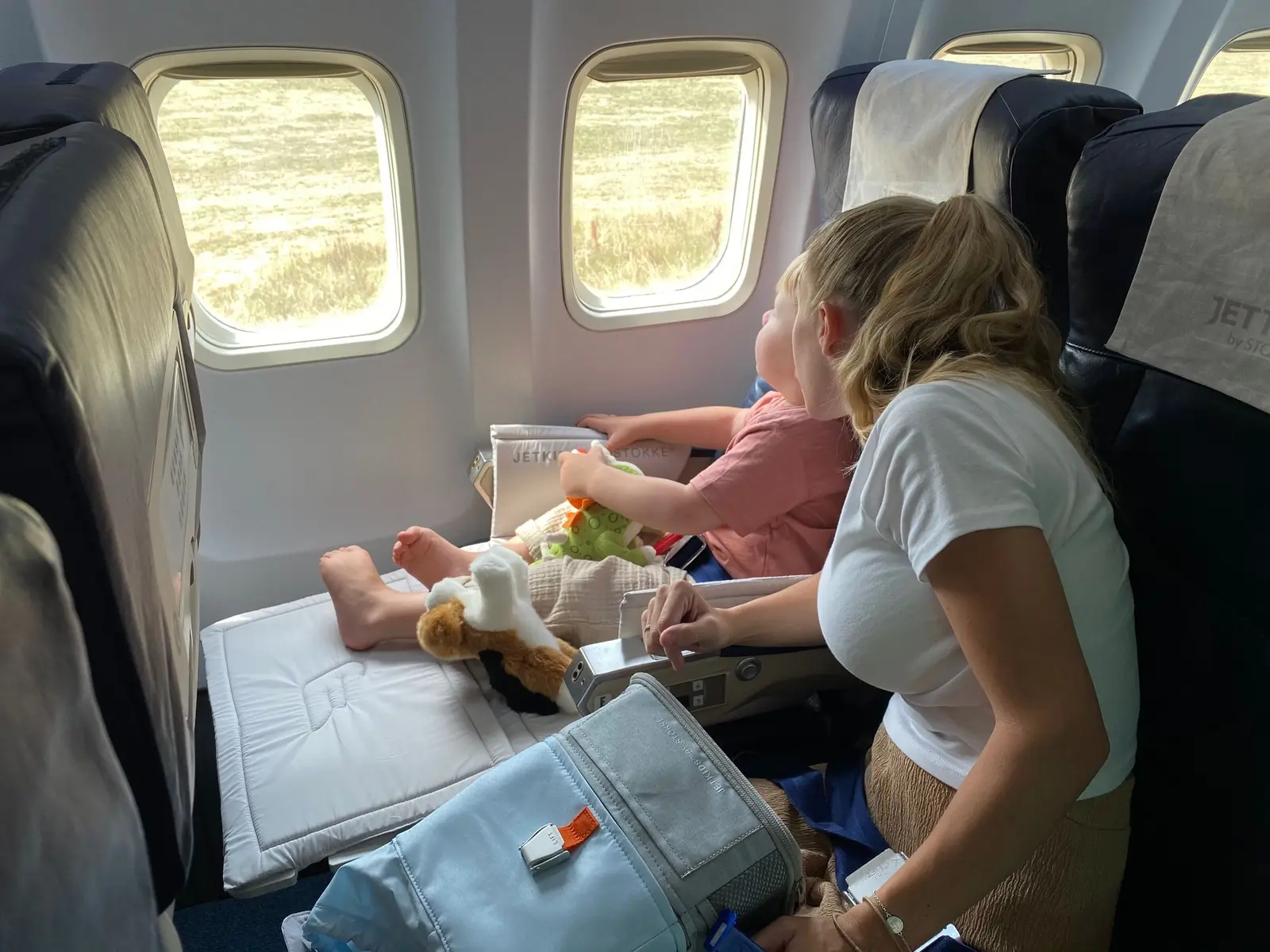 A mother and baby sitting by the window on an airplane
