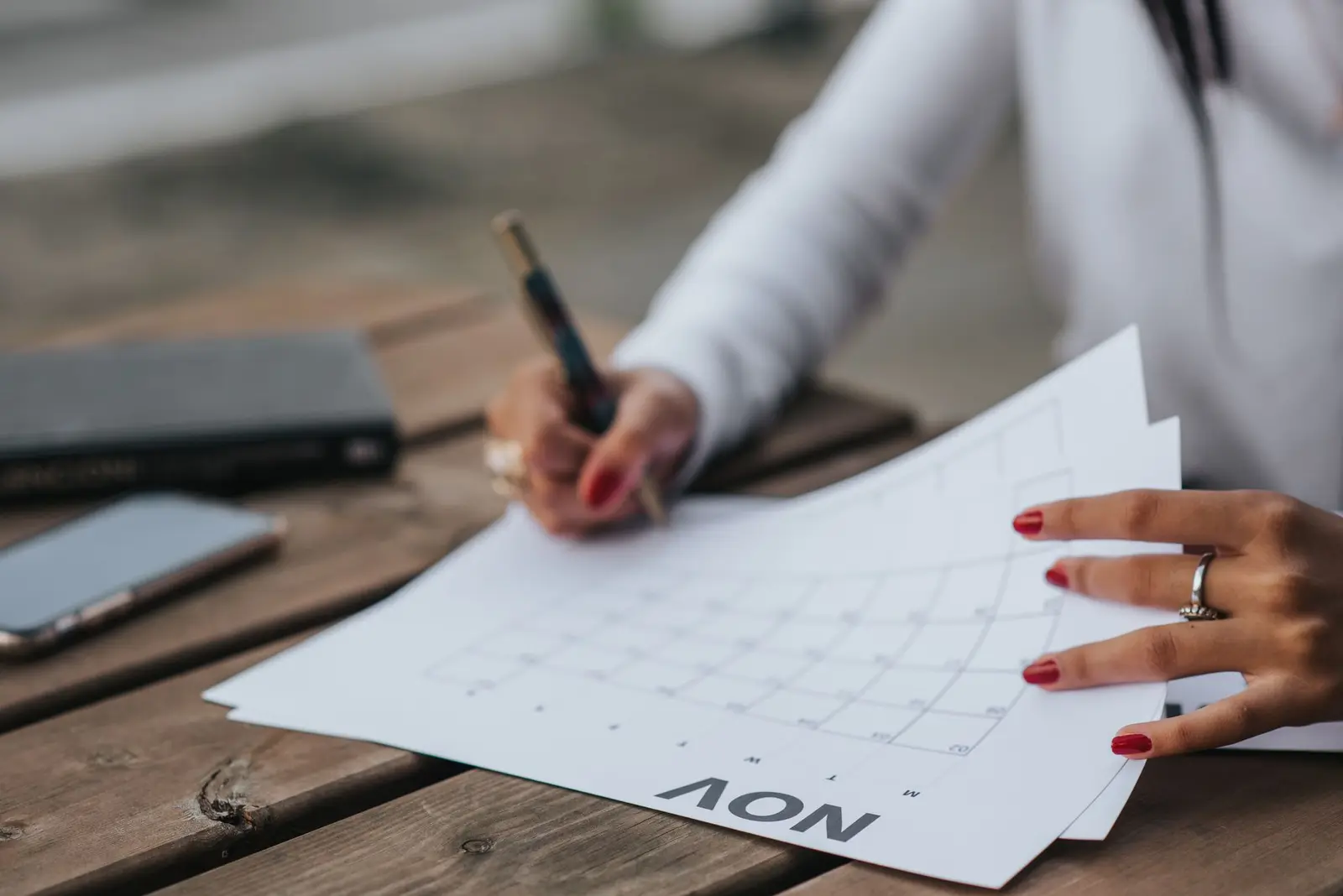 A person filling in a monthly planner at a wooden table