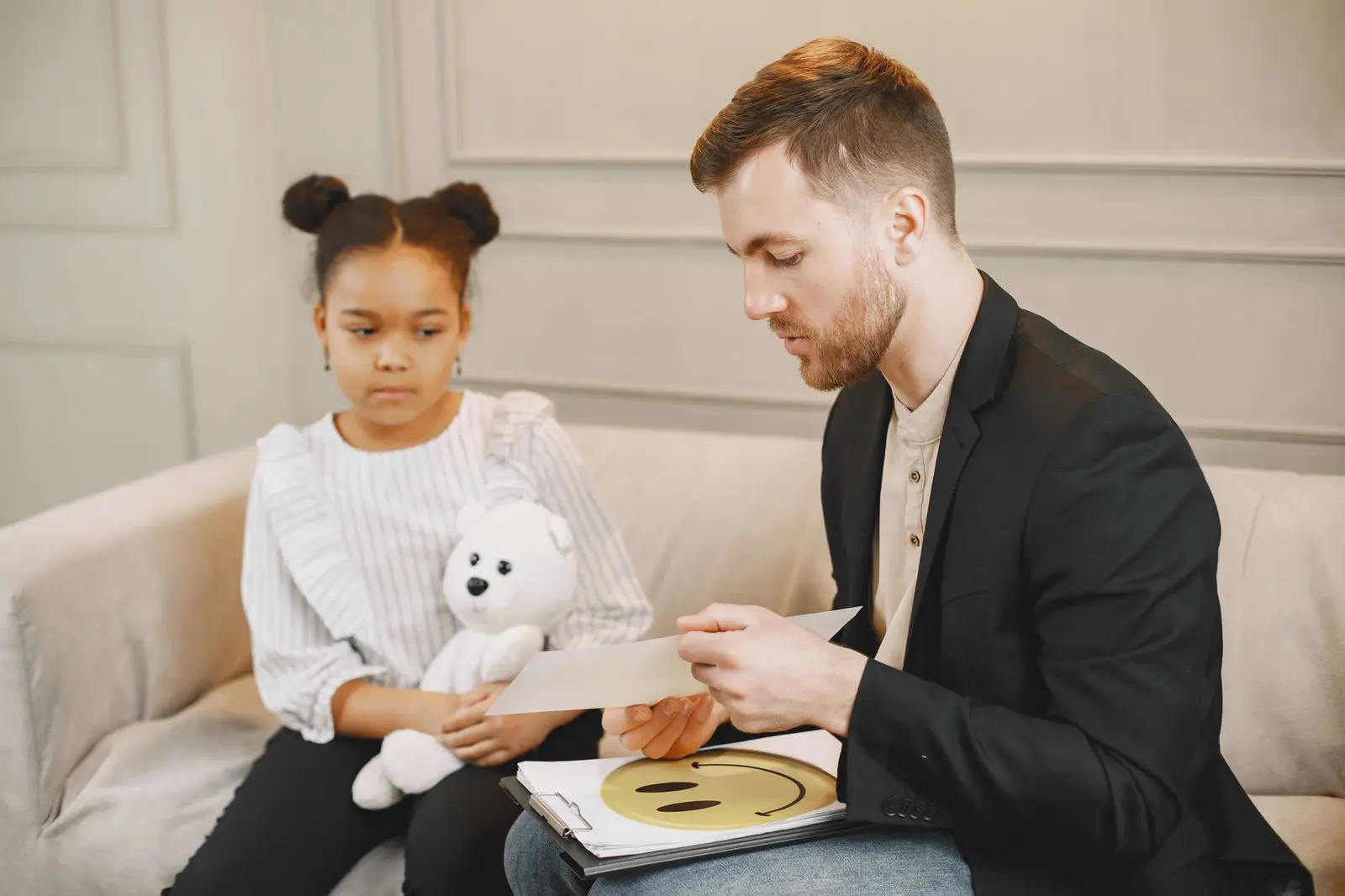A clinician talking with a young girl holding a plush toy during a session