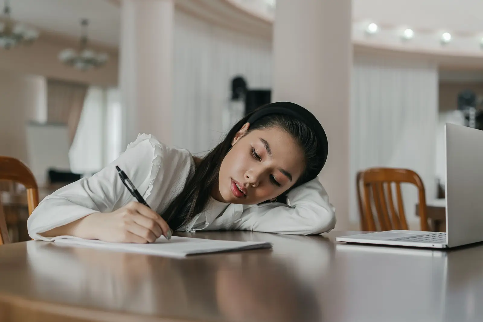 A young woman writing notes during a study session at a desk