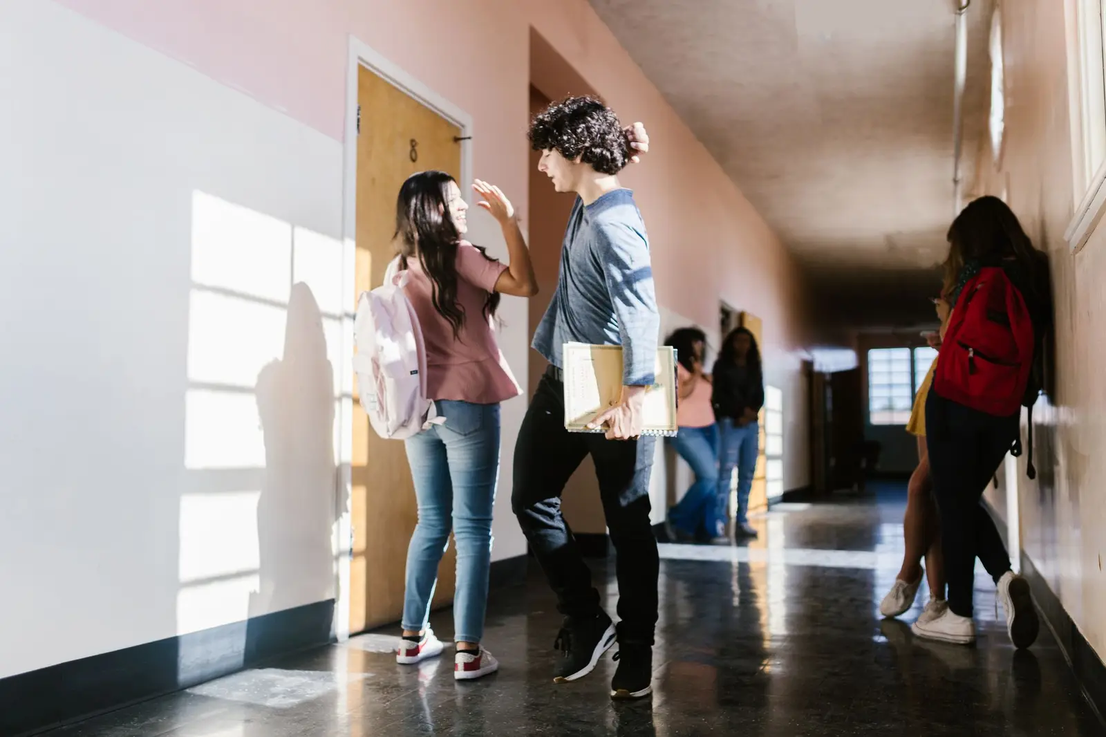 High school students talking in a bright school hallway