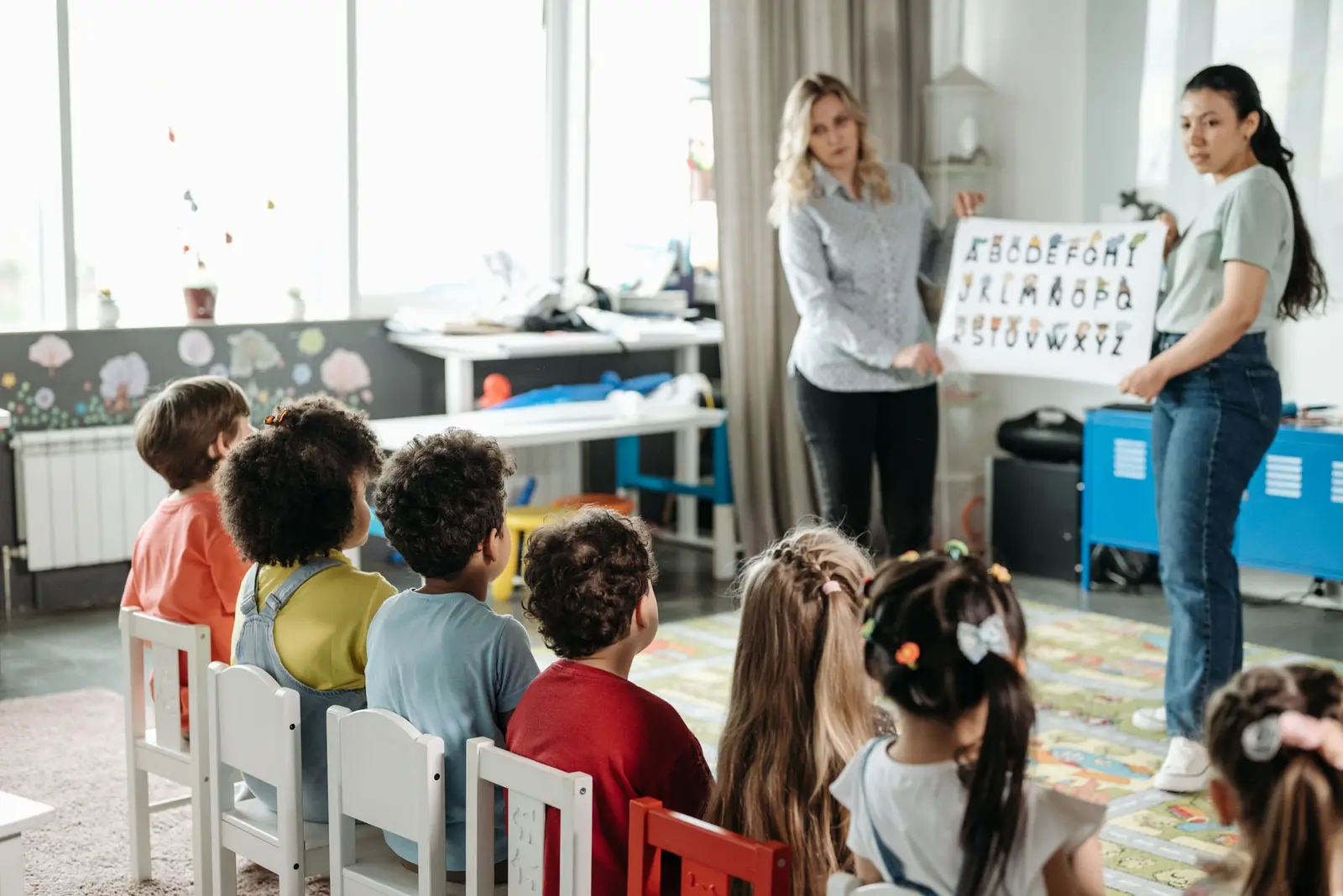Two teachers showing a picture card to a group of young children