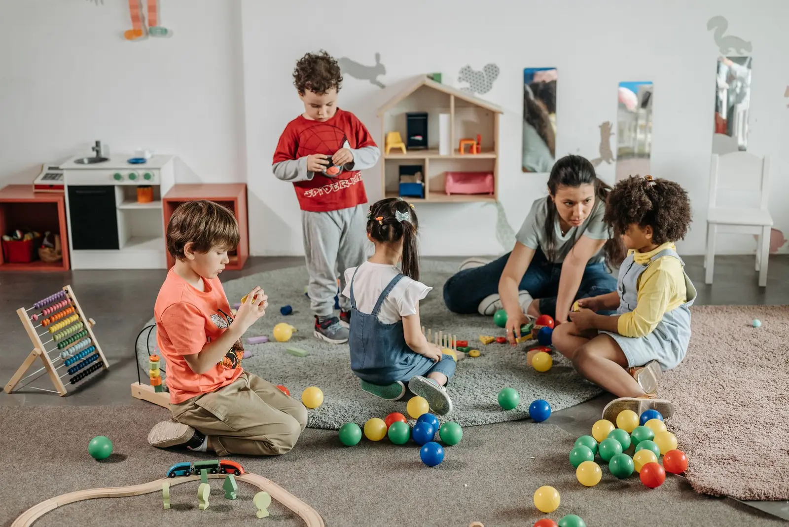 Young children and an educator playing together on the floor of a preschool room
