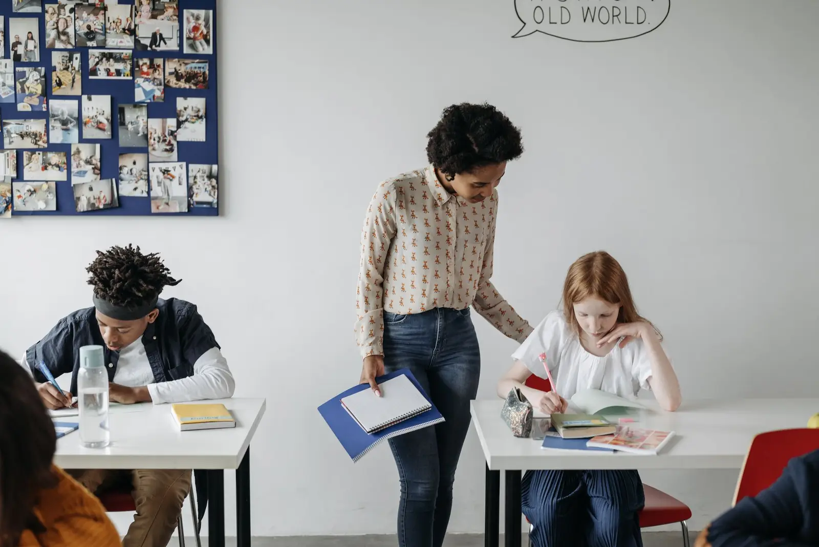 A teacher guiding students working at desks in a classroom