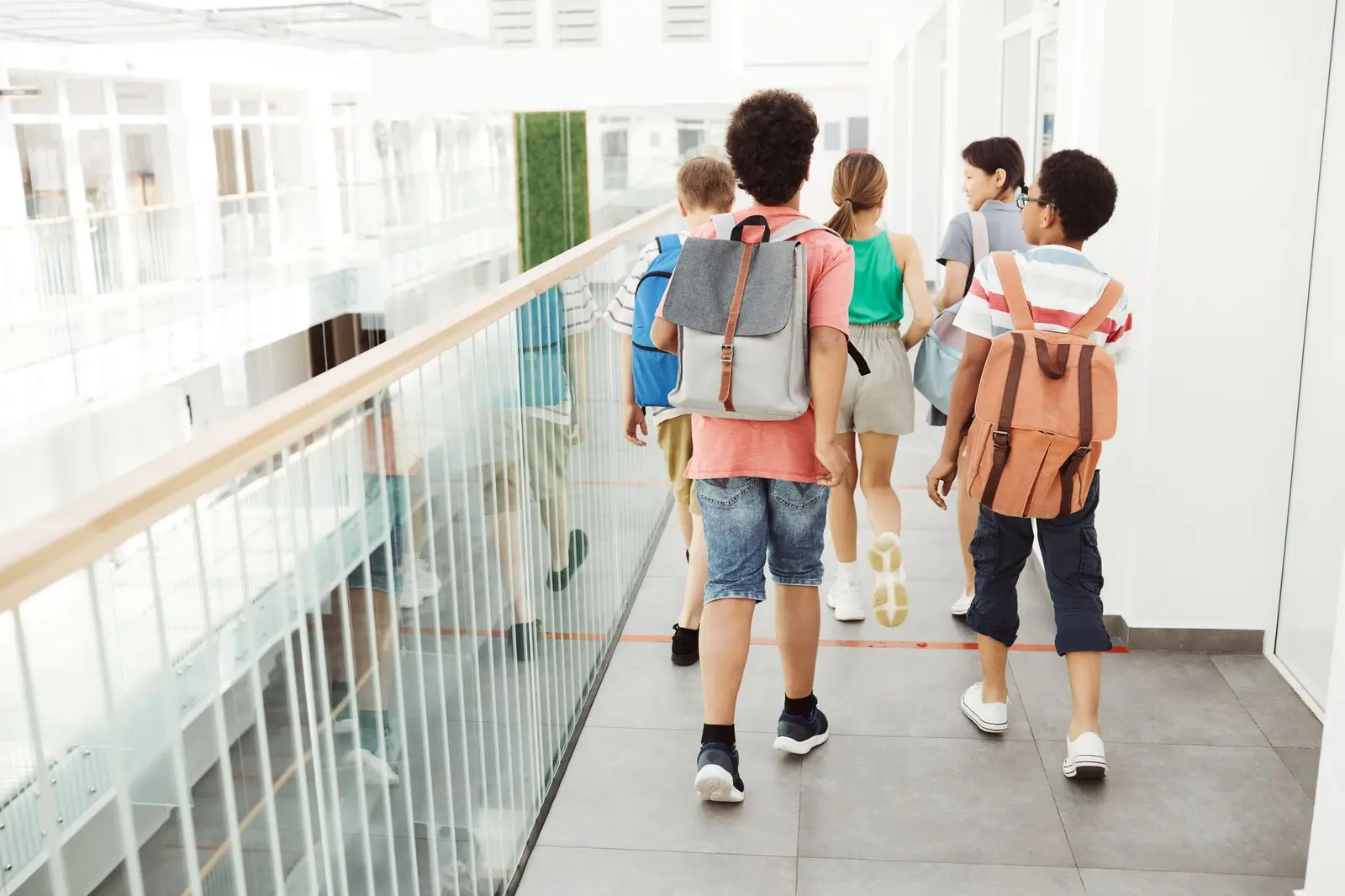 Children with backpacks walking together down a bright school hallway