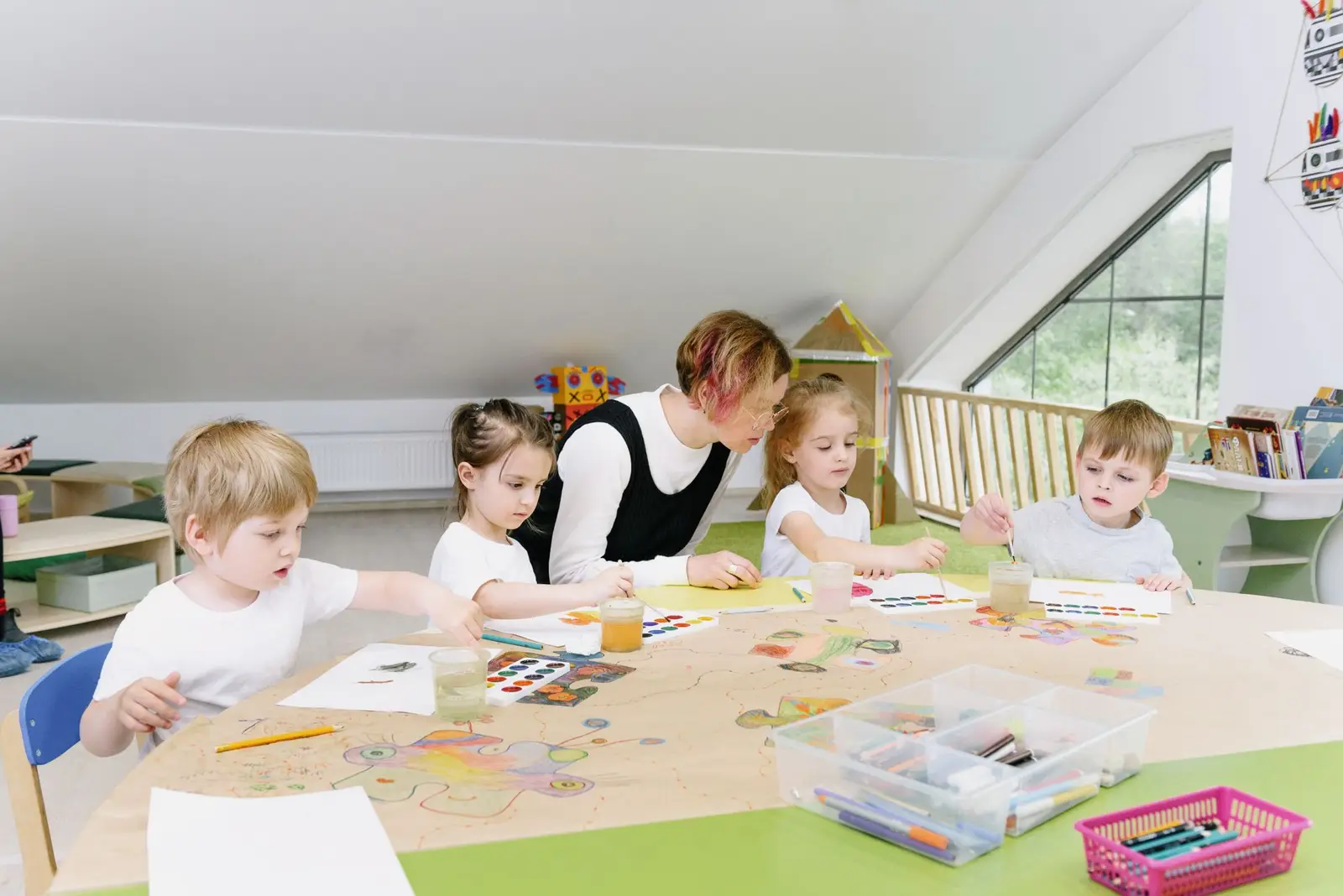 Young children doing an art activity at a table with their teacher