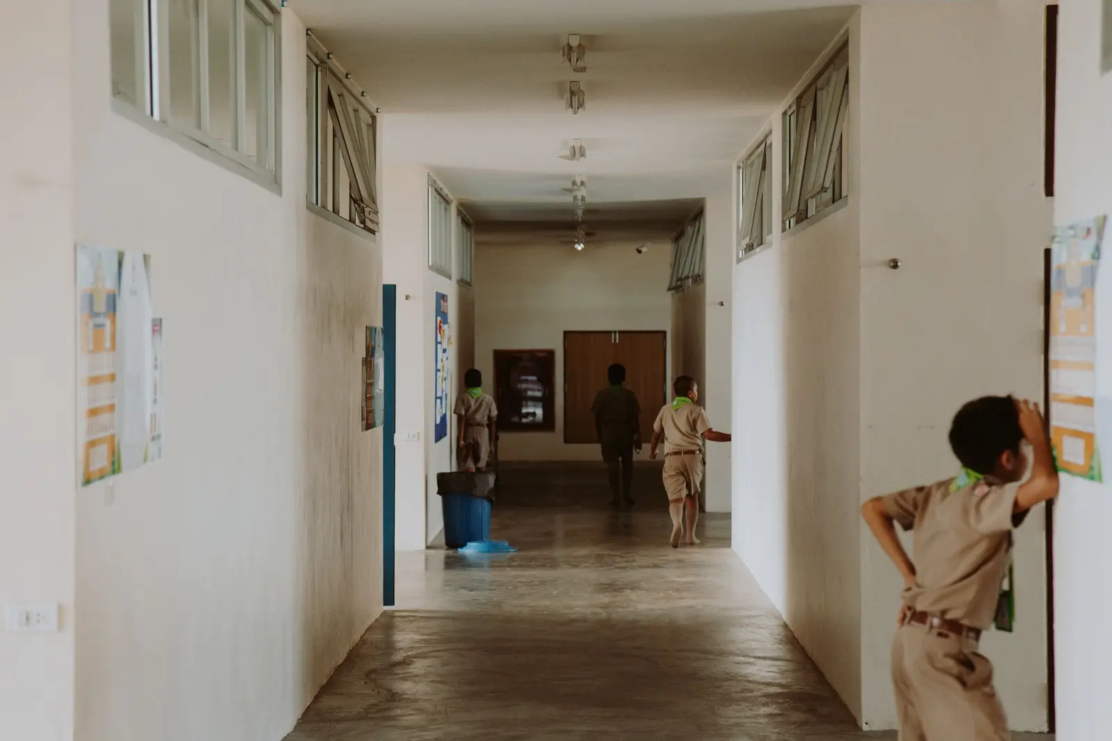 A boy in school uniform looking at posters in a quiet school corridor