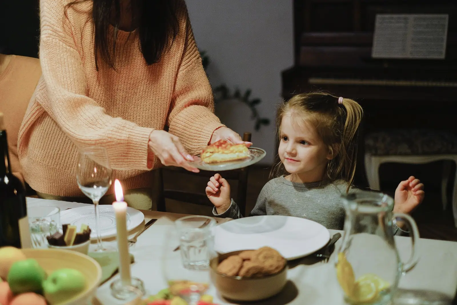 A mother serving dinner to her young daughter at the table