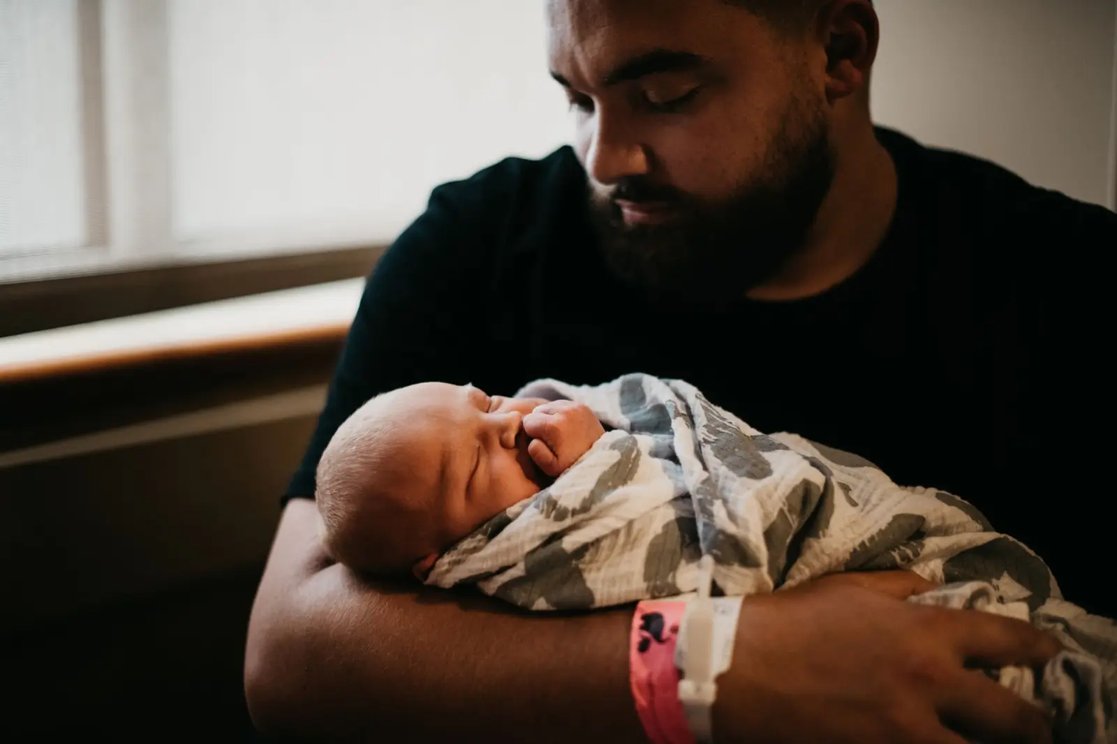 A father holding his newborn baby wrapped in a blanket