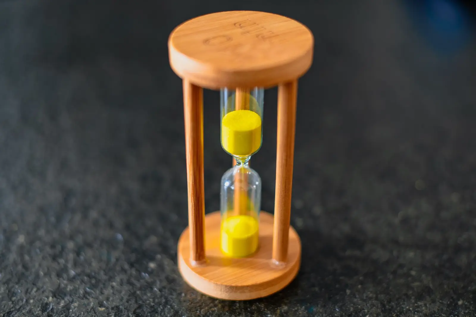 A wooden hourglass with yellow sand