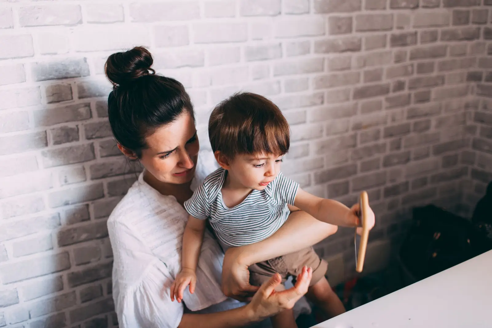 A mother holding her toddler on her lap indoors