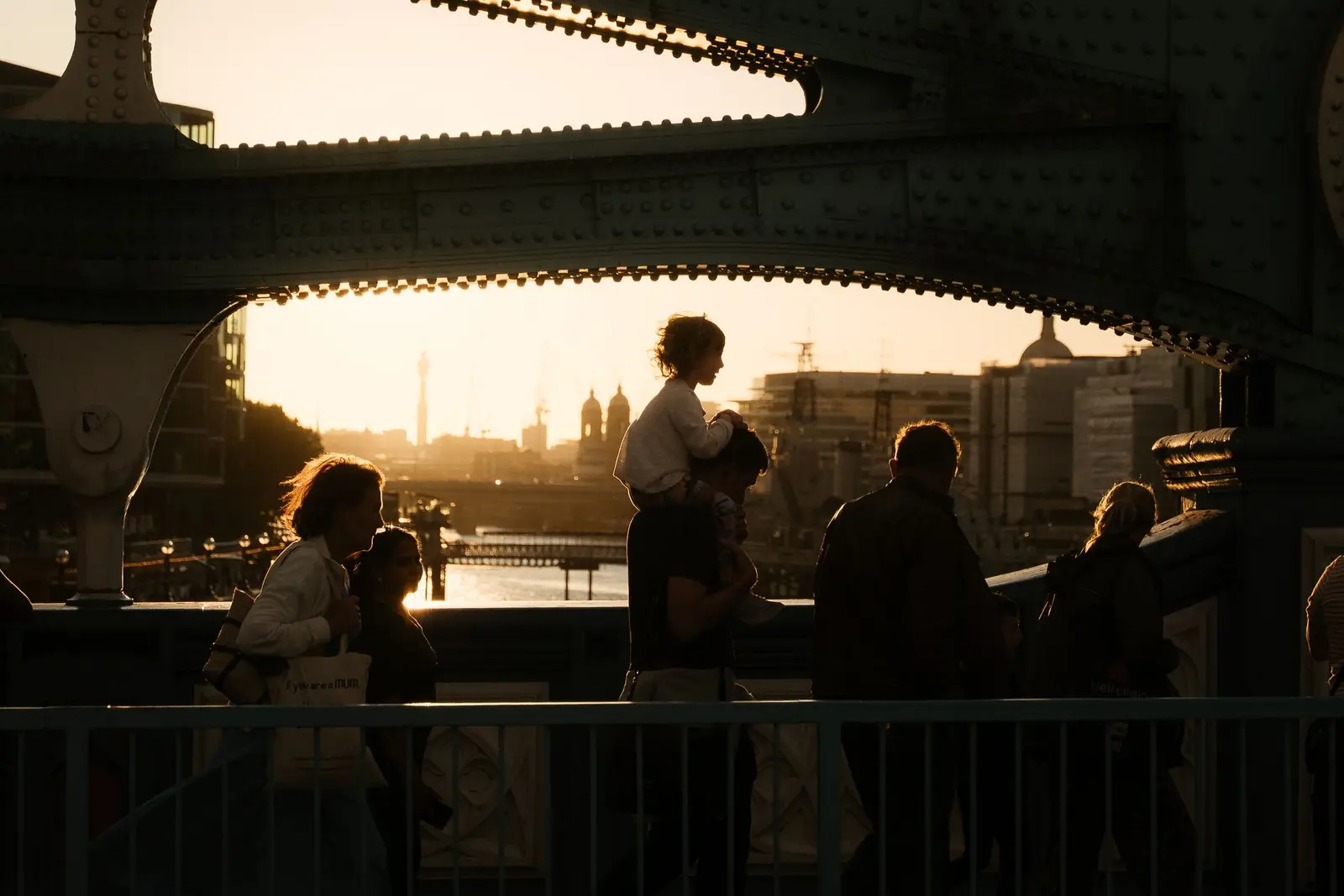 People silhouetted walking across a London bridge at sunset