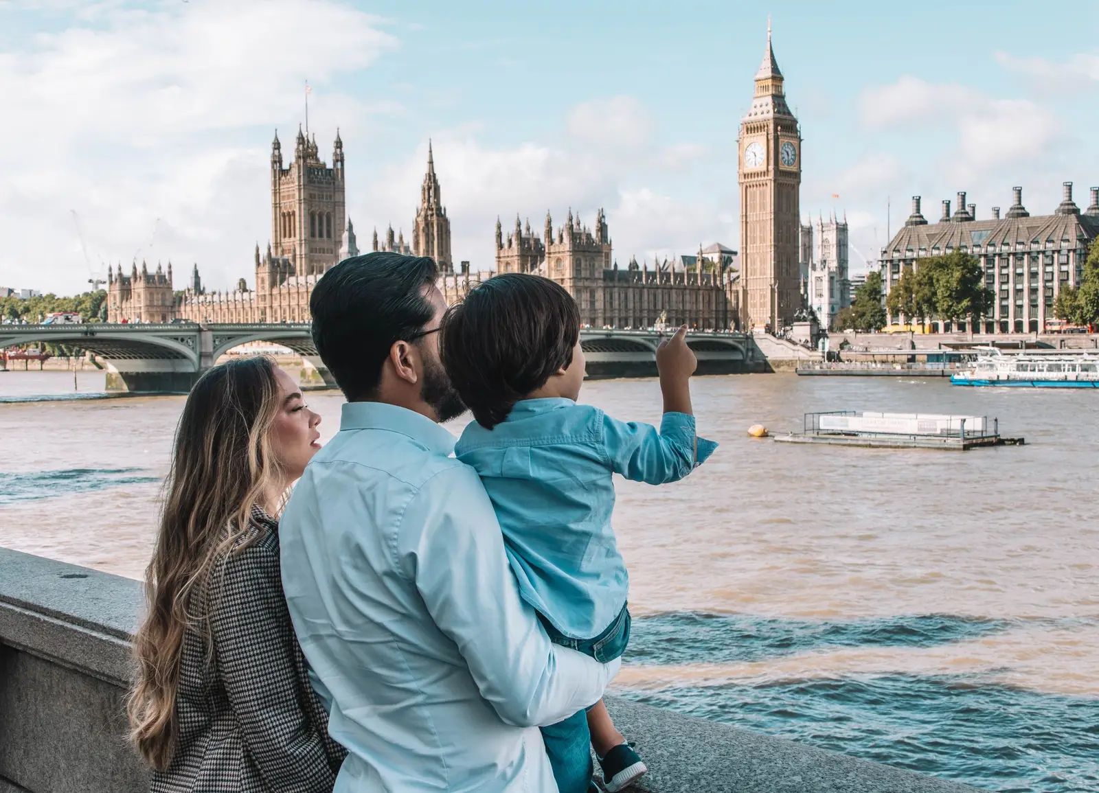 A family by the river in London looking towards the Houses of Parliament