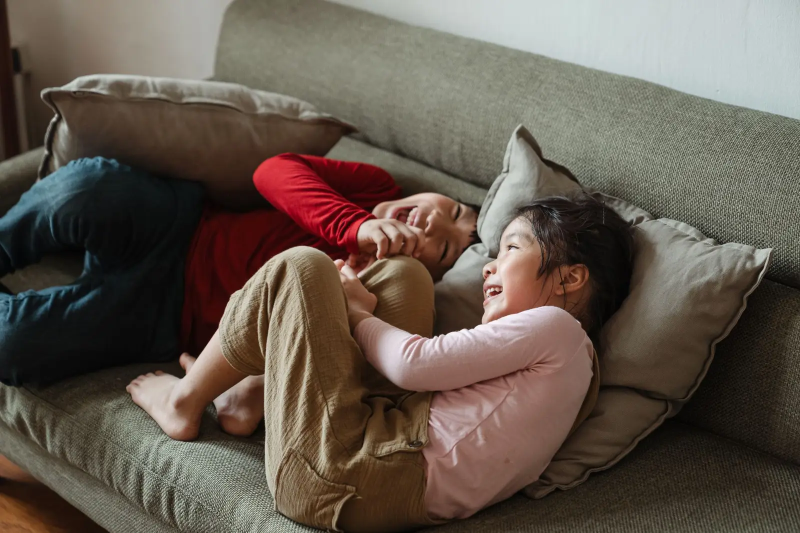 Two children laughing together on a sofa