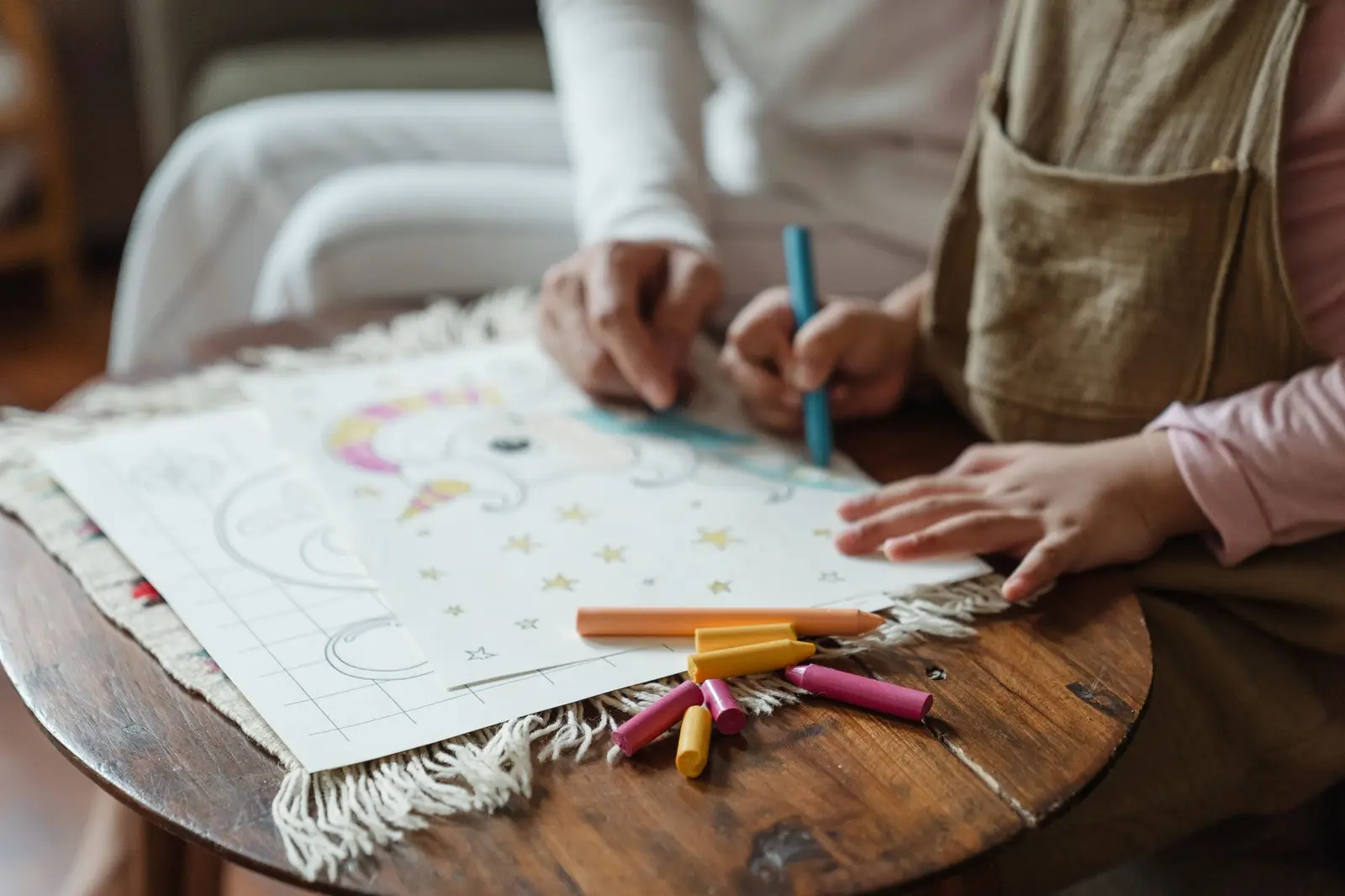 A child and parent drawing pictures together on paper at a small table