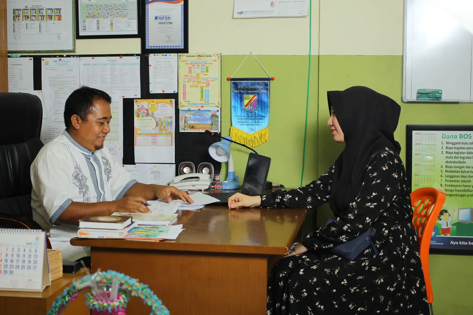 A parent meeting a teacher across a desk in a school office