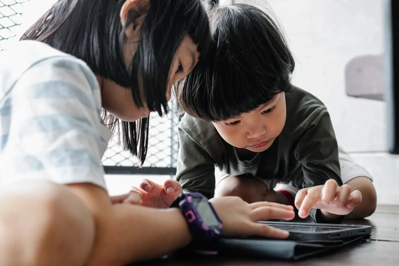 Two children tapping on a tablet together
