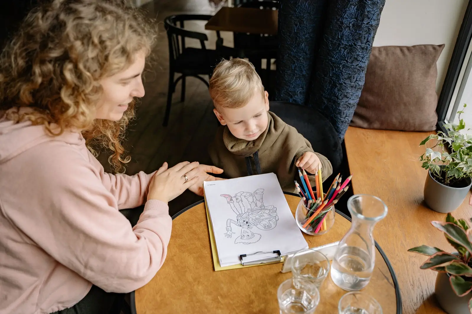 An adult and a young boy coloring a picture together at a table
