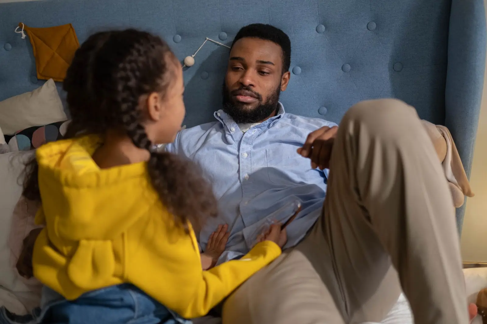 A father and daughter talking together in a cozy bedroom