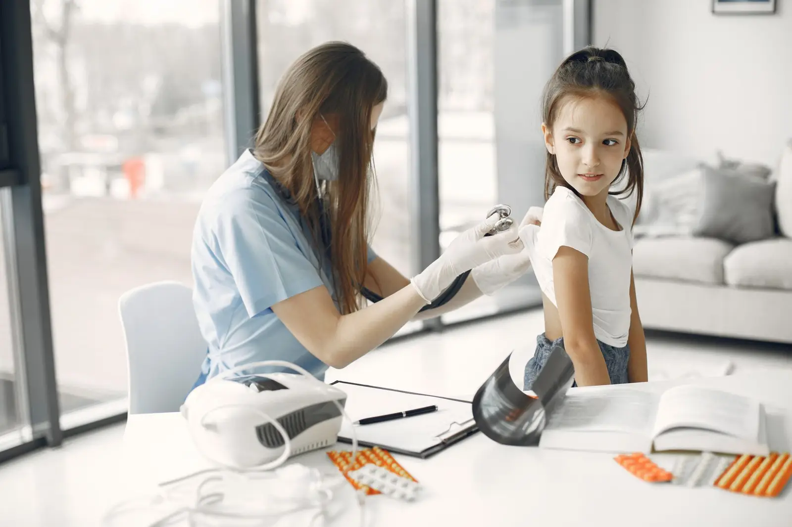 A health worker using a medical device on a girl's arm at a clinic