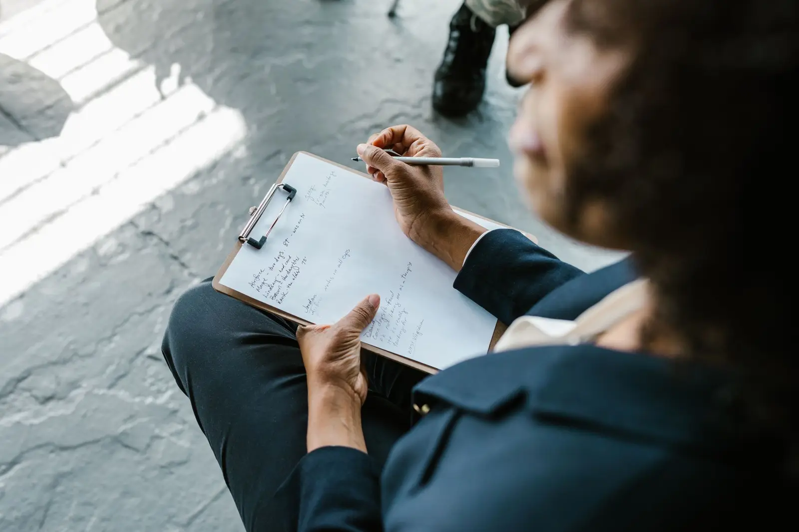 A professional writing notes on a clipboard during a meeting