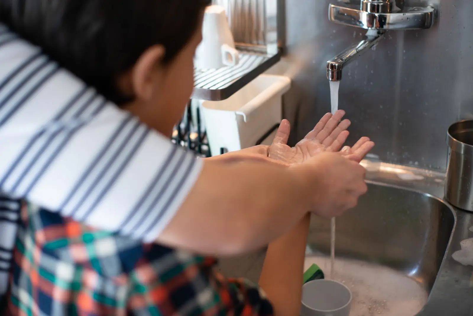 A child washing his hands at a kitchen sink