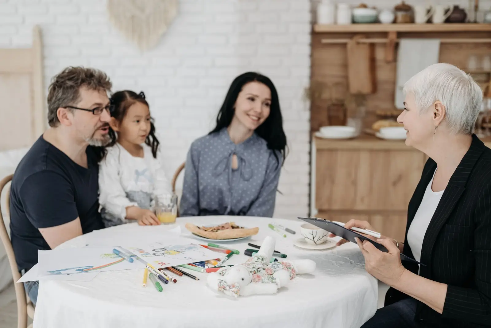 A family with a young child meeting with a professional at a kitchen table