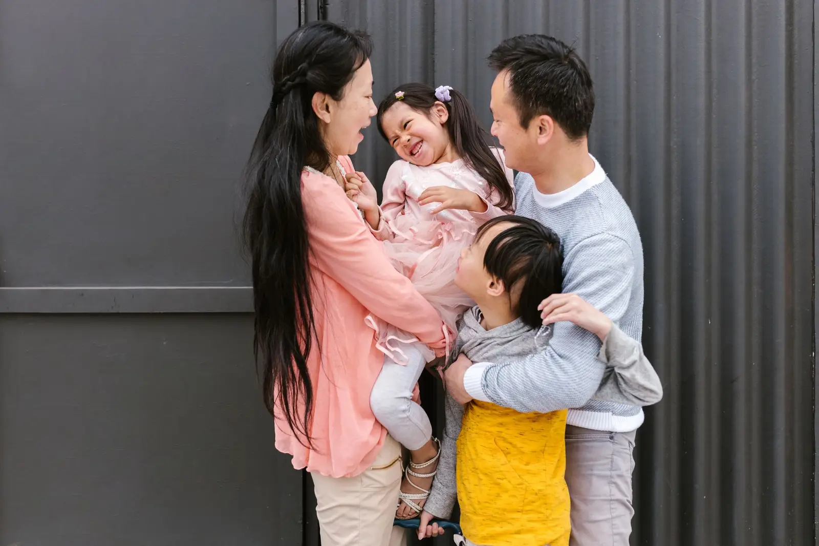 A smiling family hugging together, parents holding two young children