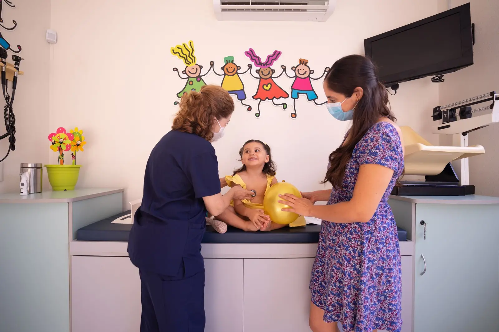 A doctor checking a young child on an examination table with a parent beside them