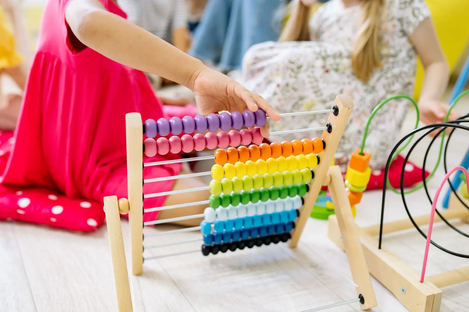 Children playing with a colorful abacus in a preschool classroom