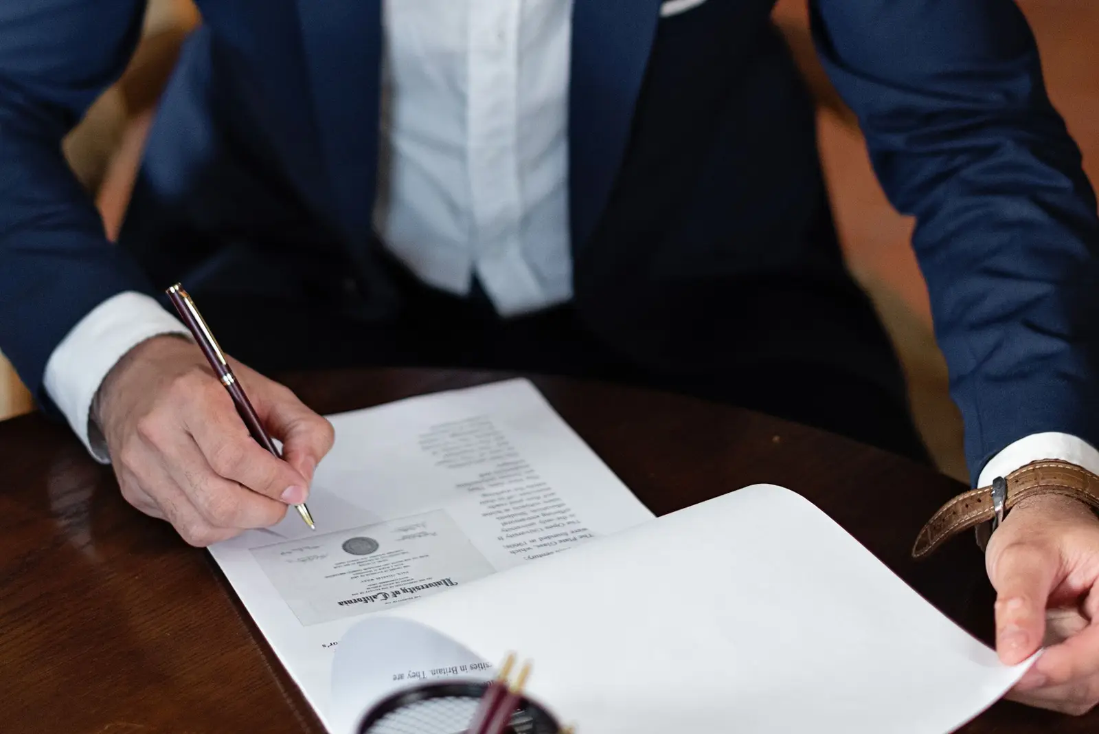 A person reading and signing documents at an office desk