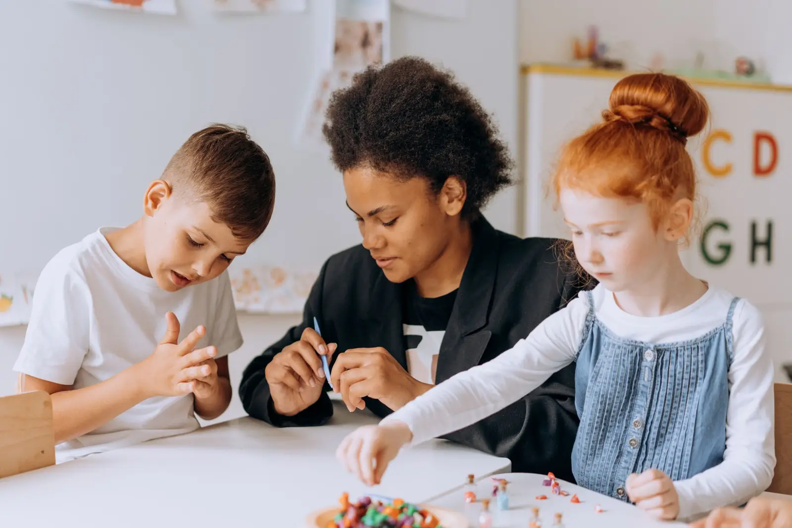 An adult working with two children on a craft activity at a table